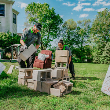 Two men working with furniture on a grassy area outdoors
